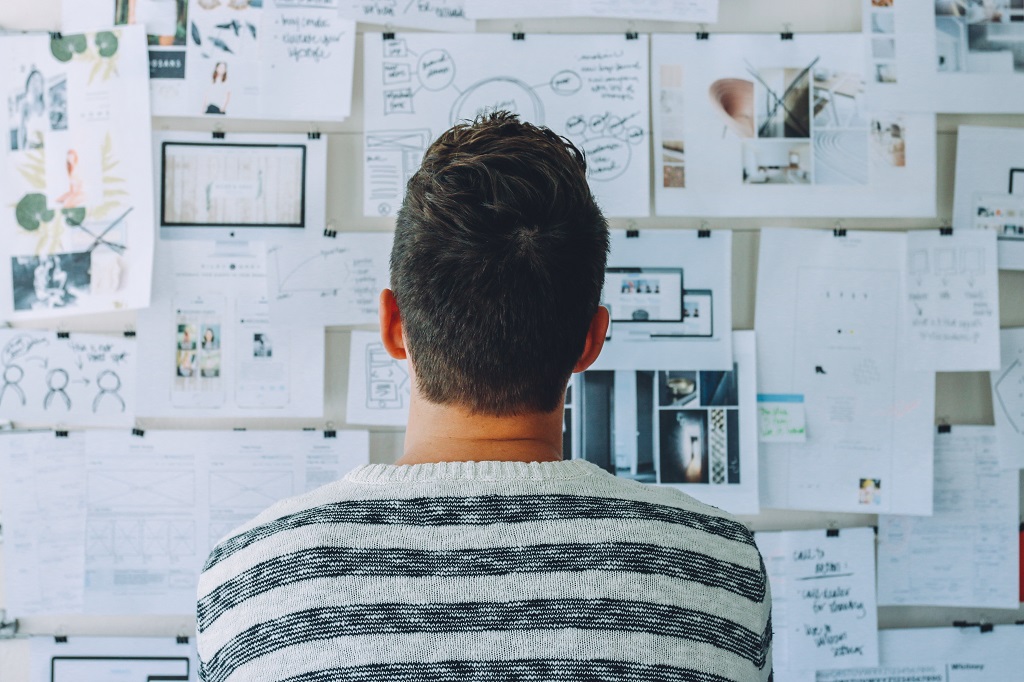 Person looking at a bulletin board full of ideas for blogs on pieces of paper